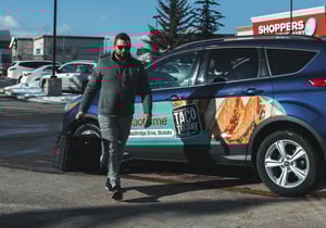 Food delivery driver walking past vehicle wrap advertisement